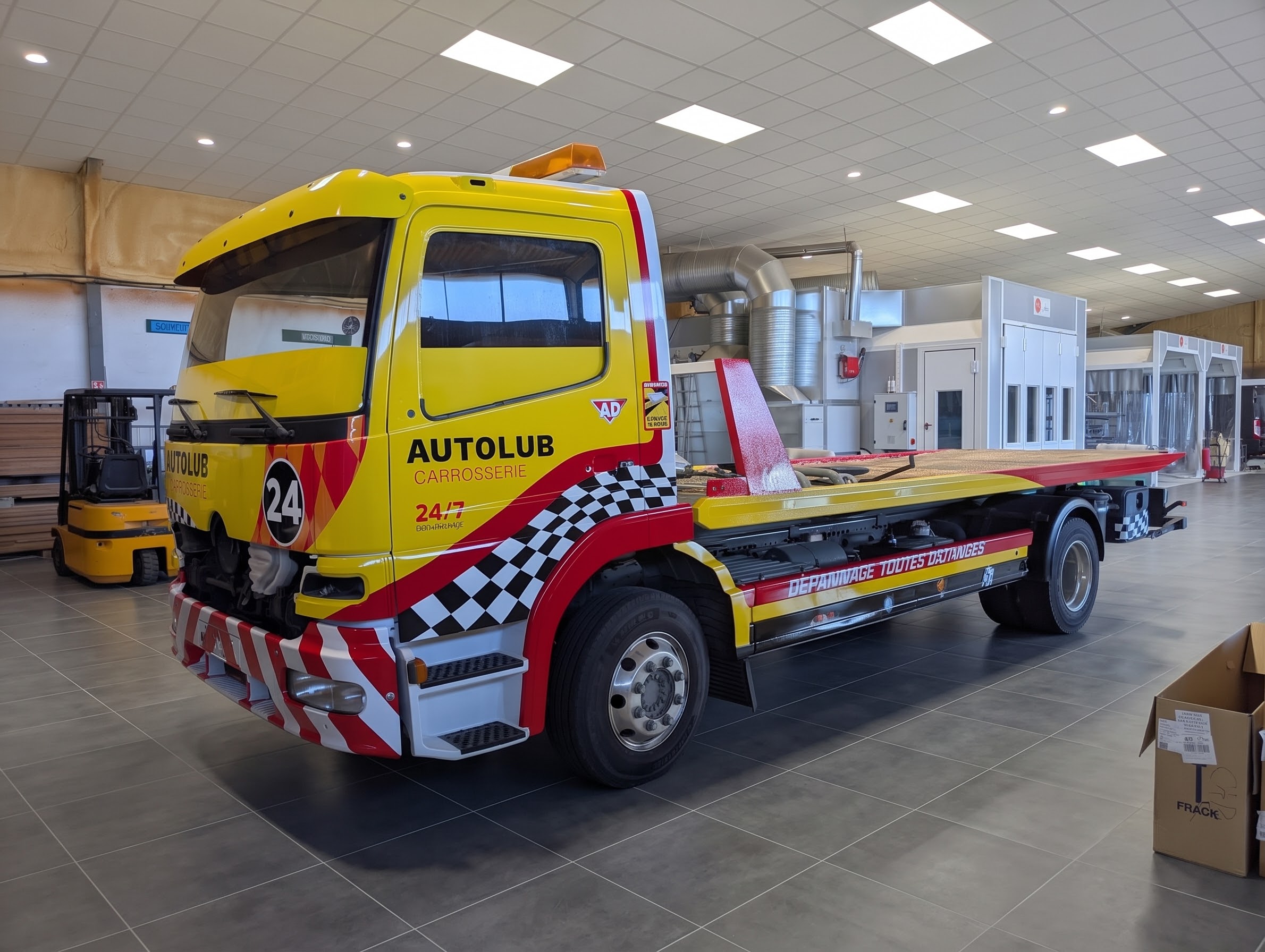 Camion Autolub habillé d’un marquage publicitaire jaune et rouge