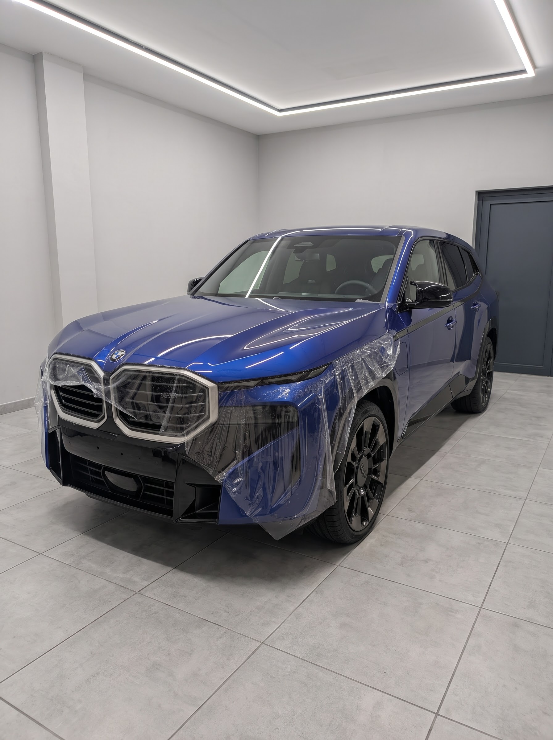 Film de protection transparent en cours de pose sur une BMW